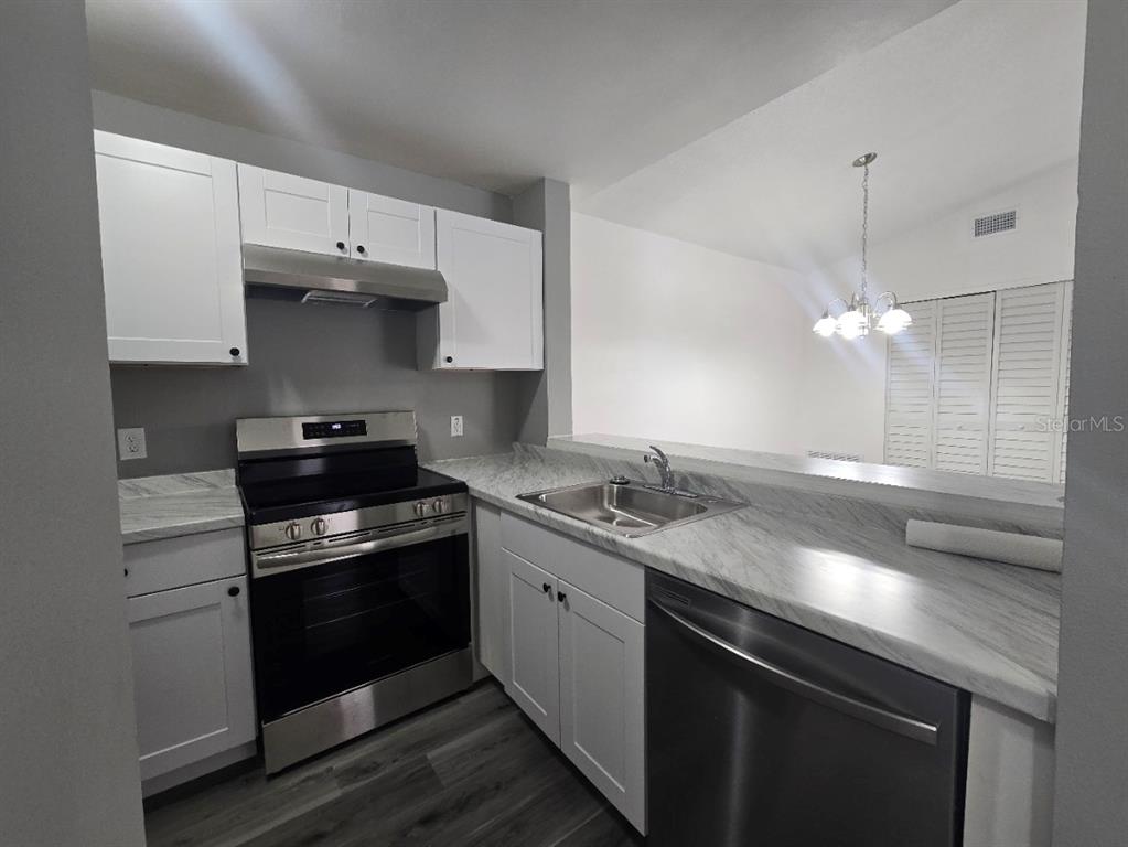 A kitchen features white cabinets, stainless steel appliances, and marble-patterned countertops — 5232 VIA HACIENDA CIRCLE UNIT A217, ORLANDO, FL