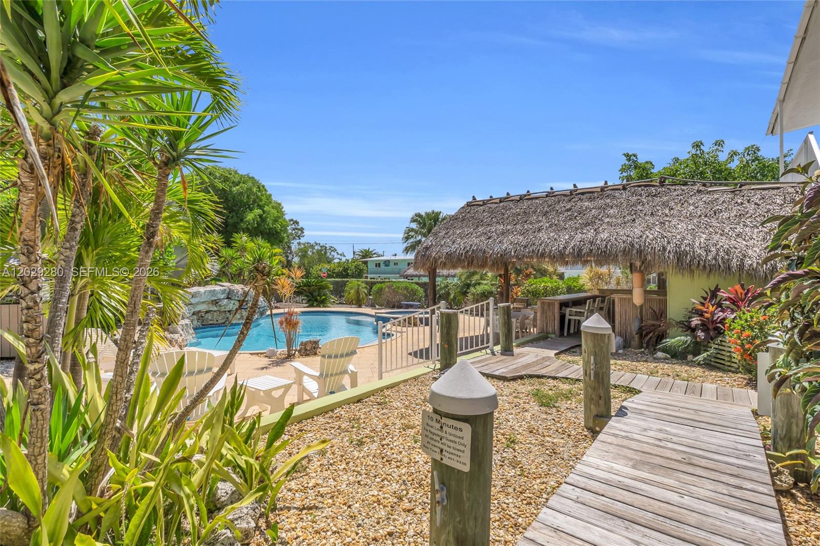 An outdoor area features a swimming pool, a tiki hut bar, and a wooden walkway — 443 4TH Rd, Key Largo FL 33037, KEY LARGO, FL