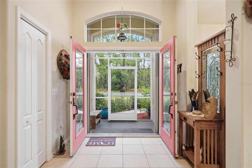 An entryway features double pink doors opening to a screened porch with tiled flooring — 4 MILBARK DRIVE, HOMOSASSA, FL
