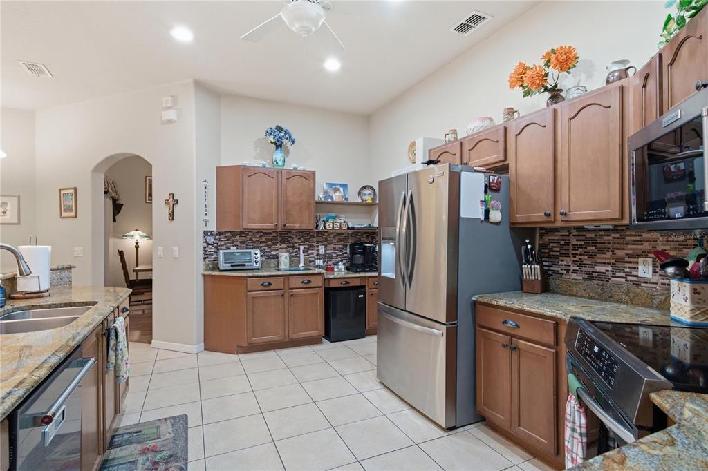 A kitchen features wood cabinets, granite countertops, stainless steel appliances, and a tiled floor — 4 MILBARK DRIVE, HOMOSASSA, FL