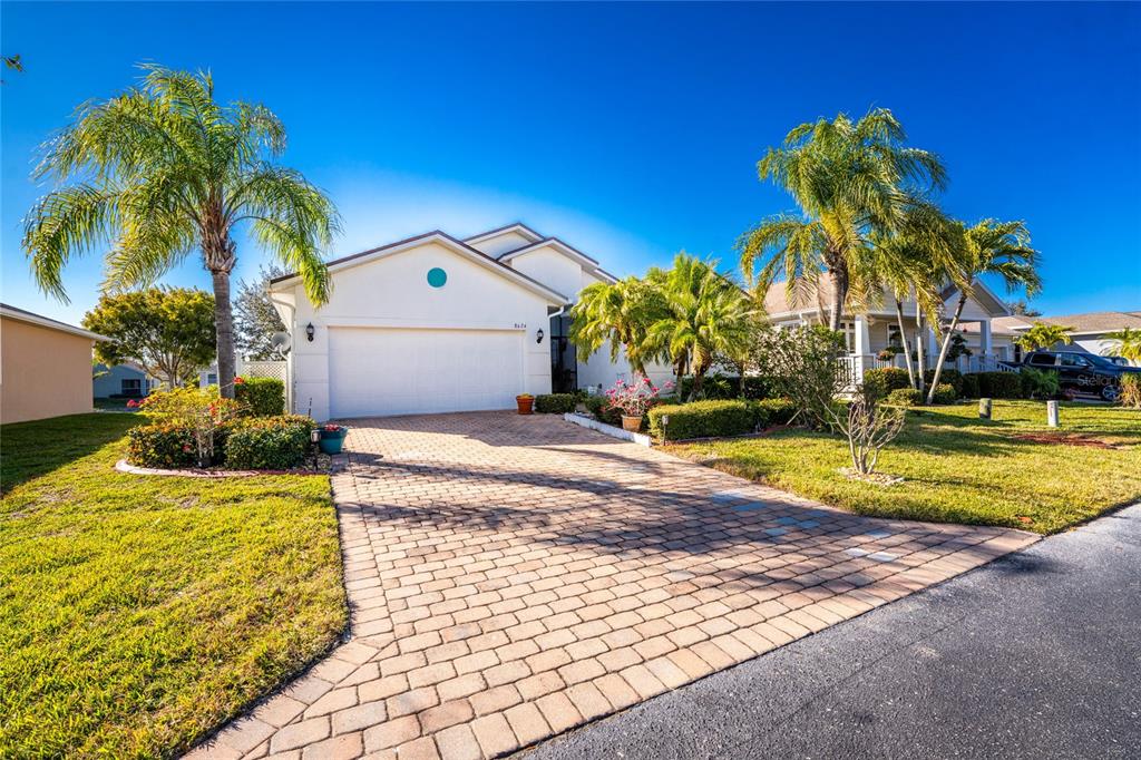 A single-story house with a white exterior, a paved driveway, and several palm trees — 8624 LAKE FRONT COURT, PUNTA GORDA, FL