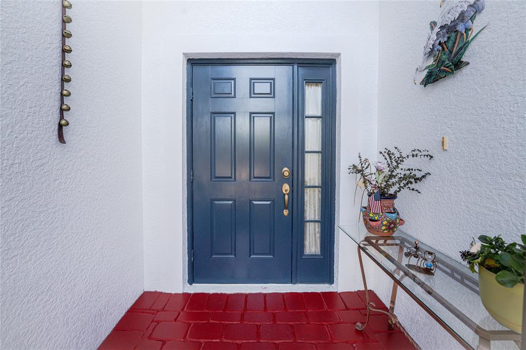 A blue front door with a side window sits above a red tiled entryway floor — 8624 LAKE FRONT COURT, PUNTA GORDA, FL