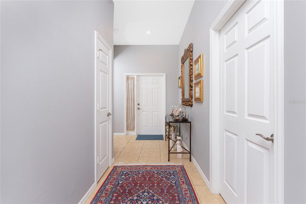 A foyer features gray walls, tile flooring, a patterned rug, and a white front door — 8624 LAKE FRONT COURT, PUNTA GORDA, FL