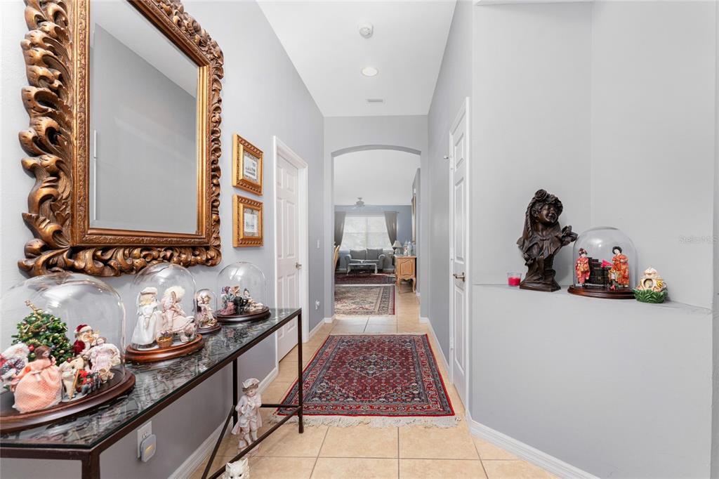 A hallway with tile flooring leads to a living area, featuring a console table display — 8624 LAKE FRONT COURT, PUNTA GORDA, FL