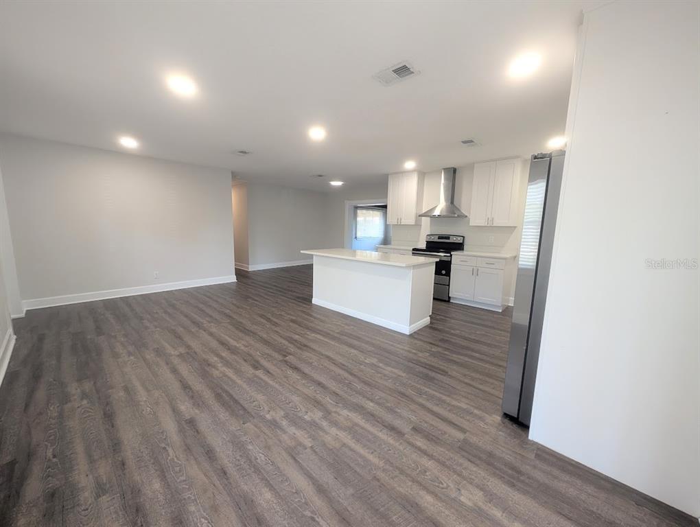 An open-concept kitchen features white cabinetry, a center island, and dark wood-look flooring — 3902 W PAXTON AVENUE, TAMPA, FL