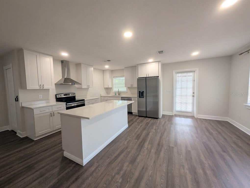 A kitchen with white cabinets and an island opens into a living area with flooring — 3902 W PAXTON AVENUE, TAMPA, FL