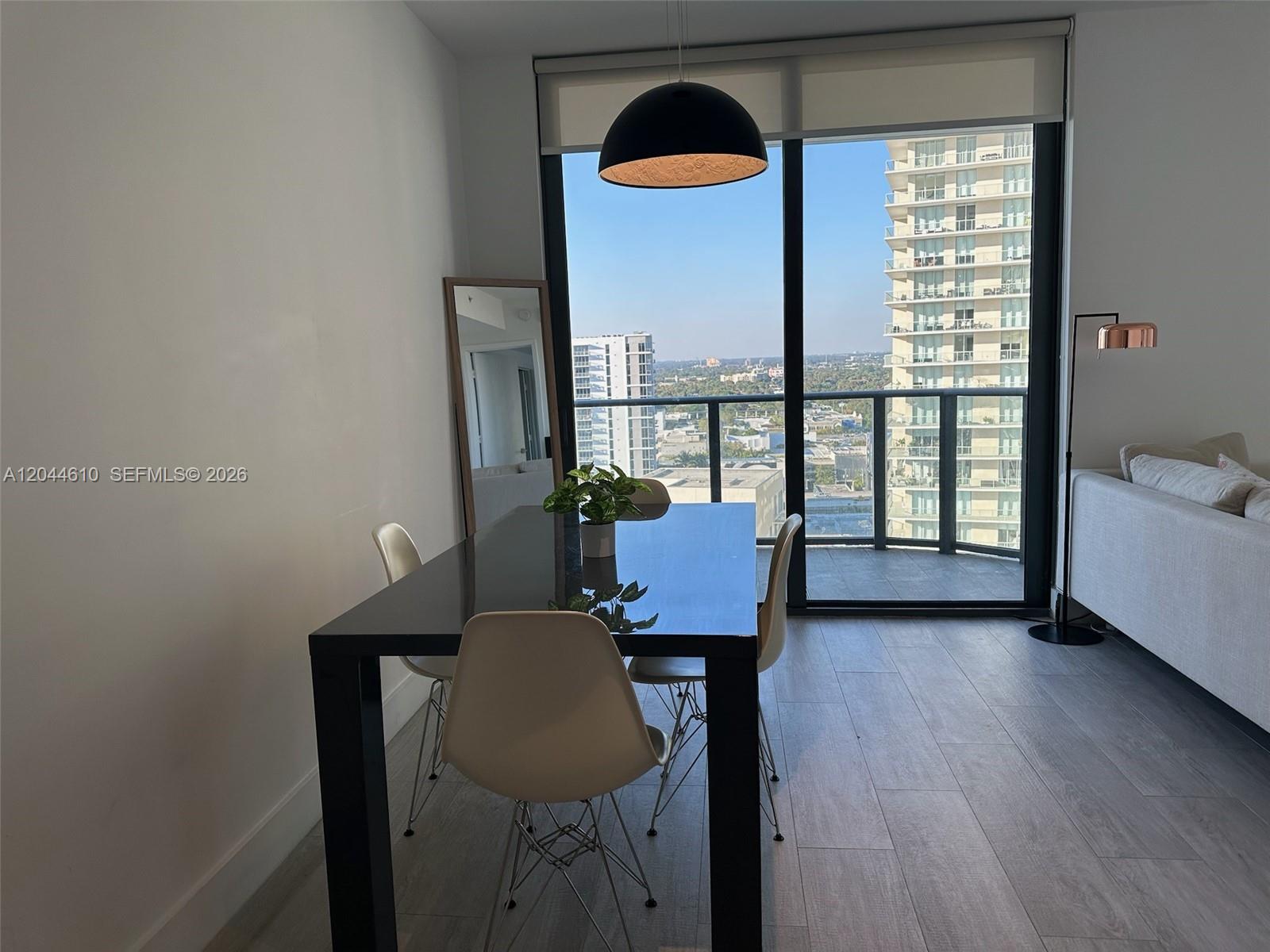 A dining area features a black table, white chairs, and a balcony with city views — 121 NE 34th St # 1915, Miami FL 33137, MIAMI, FL