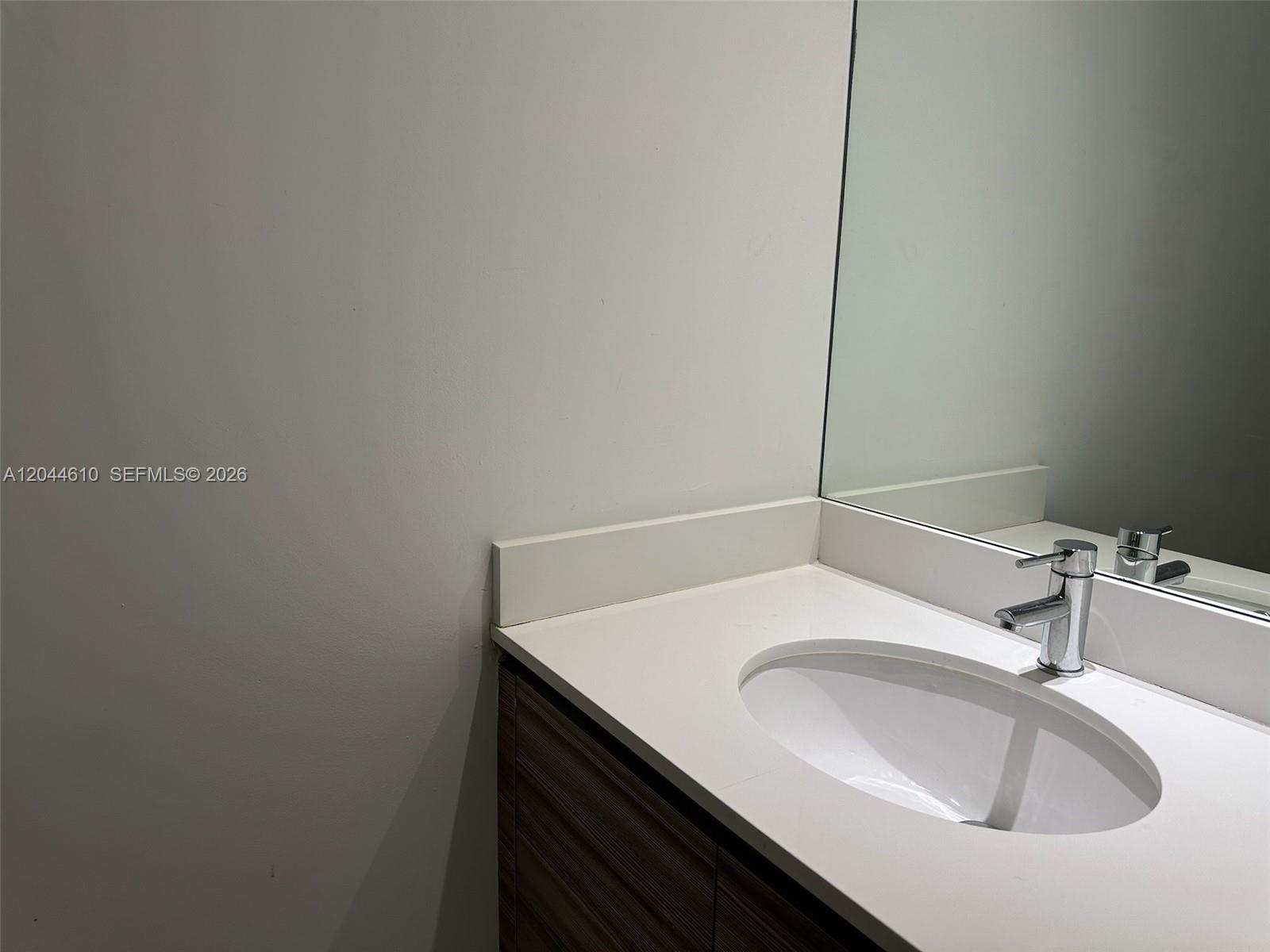 A bathroom vanity features a white countertop, an oval sink, and a chrome faucet — 121 NE 34th St # 1915, Miami FL 33137, MIAMI, FL