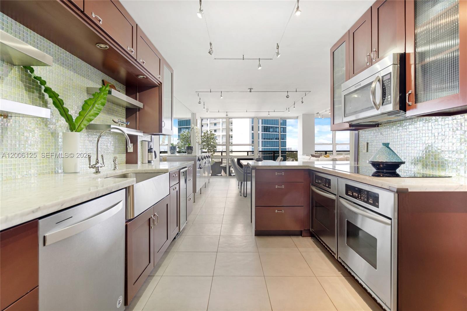 A modern kitchen features dark wood cabinets, stainless steel appliances, and a view of buildings — 600 NE 36th St, Miami FL 33137, MIAMI, FL