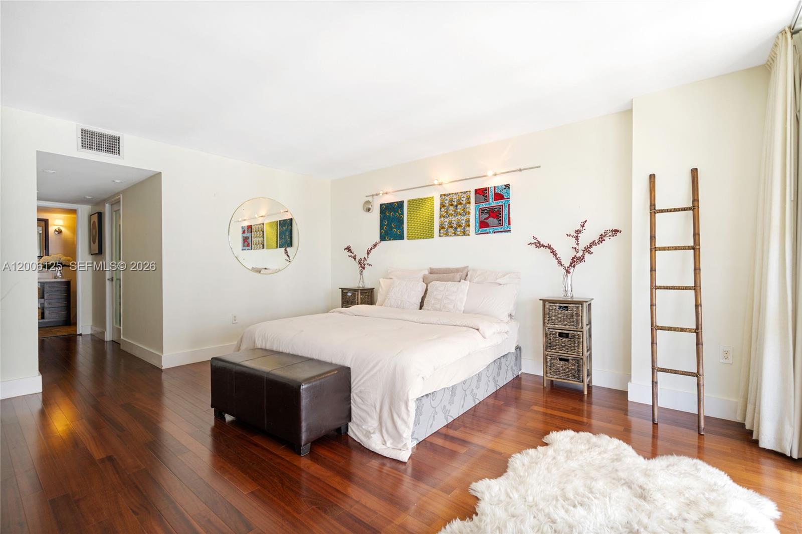 A bedroom features a bed with a patterned base, dark wood floors, and a decorative ladder — 600 NE 36th St, Miami FL 33137, MIAMI, FL