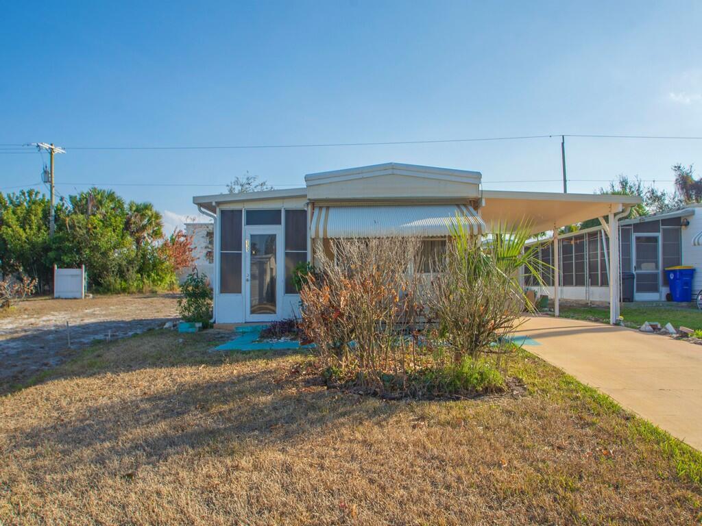 A single-story mobile home with a carport and a screened-in front porch — 335 NE Tropicalia Lane, Jensen Beach FL 34957, JENSEN BEACH, FL