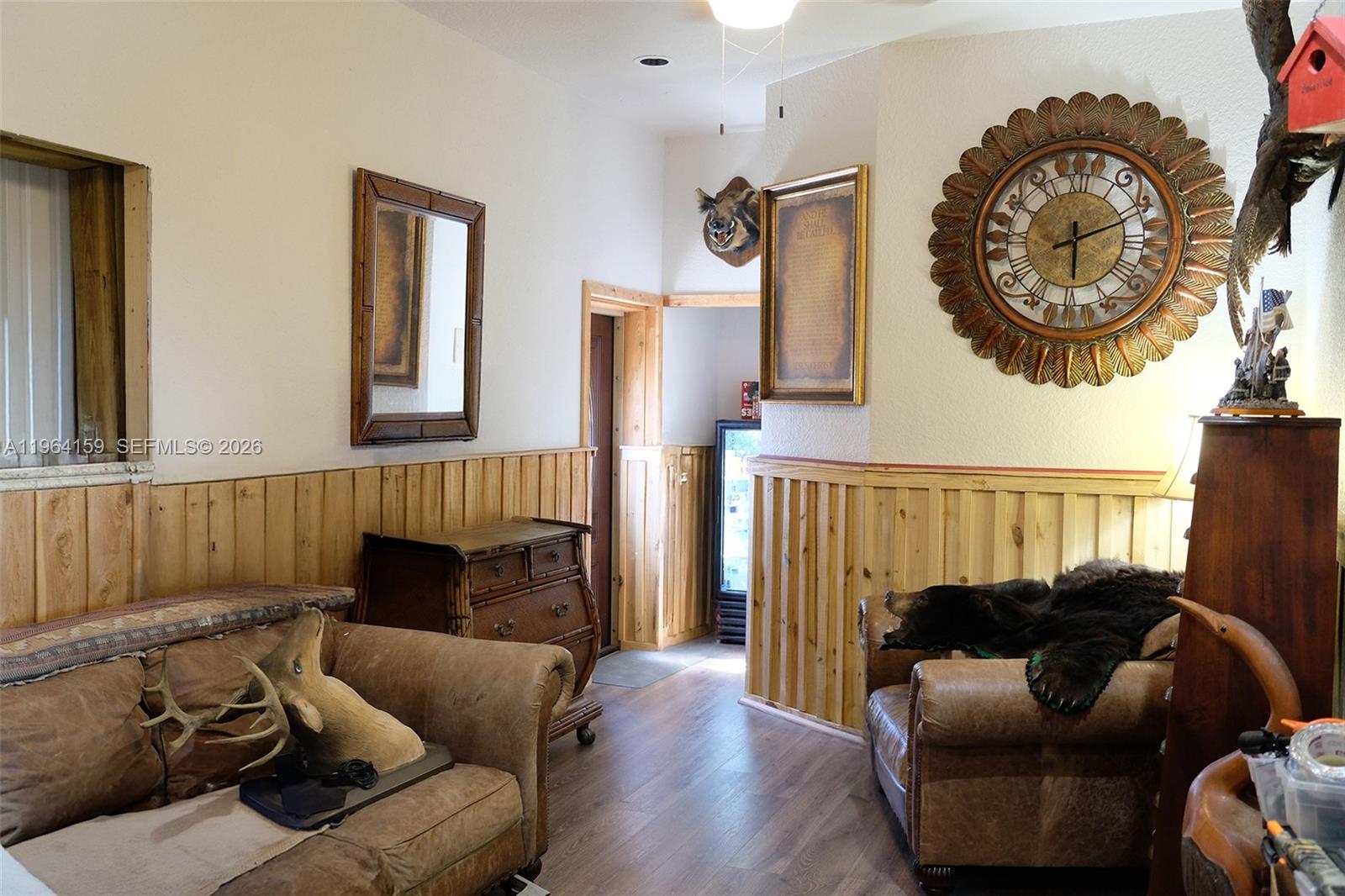 A rustic room features wood wainscoting, leather furniture, taxidermy, and a large decorative wall clock — 5271 US HWY 441 SE, Okeechobee FL 34974, OKEECHOBEE, FL