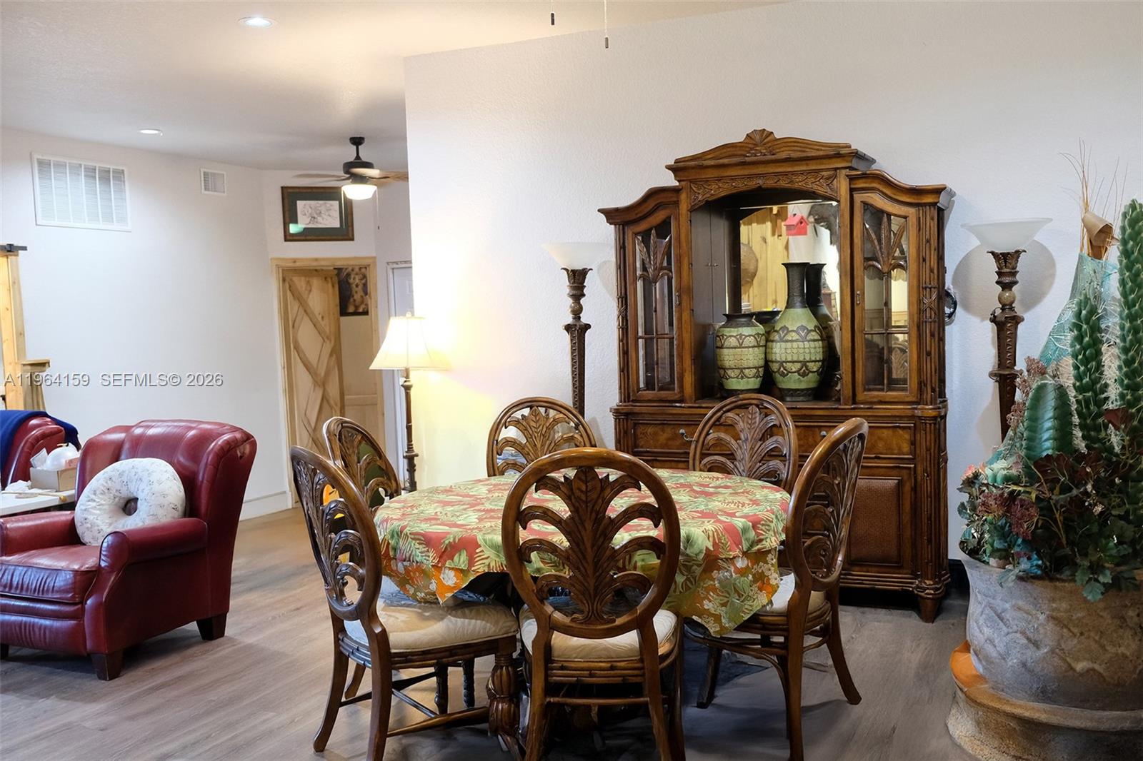 A dining room features a round table with chairs, a wooden hutch, and a red armchair — 5271 US HWY 441 SE, Okeechobee FL 34974, OKEECHOBEE, FL