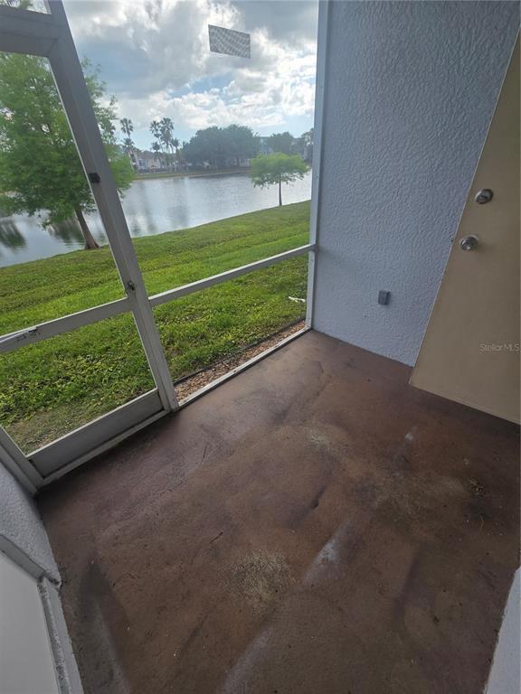A screened-in patio with a concrete floor overlooks a lake and grassy landscape — 8312 BERNWOOD COVE LOOP UNIT 1007, FORT MYERS, FL