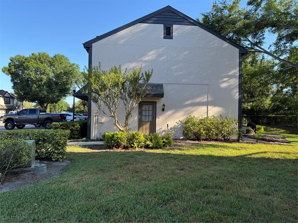 A two-story building exterior features a tan stucco facade, a dark roof, and a single door — 16573 BRIGADOON DRIVE, TAMPA, FL