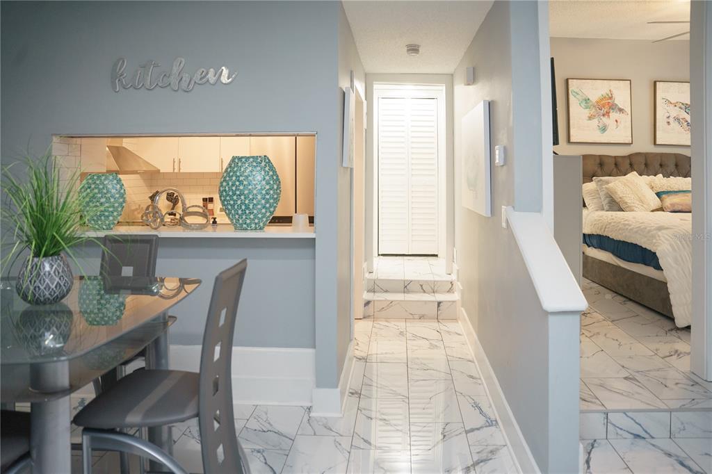 A dining area with a kitchen pass-through window leads to a hallway with tiled floors — 4405 W FAIR OAKS AVENUE UNIT 2, TAMPA, FL