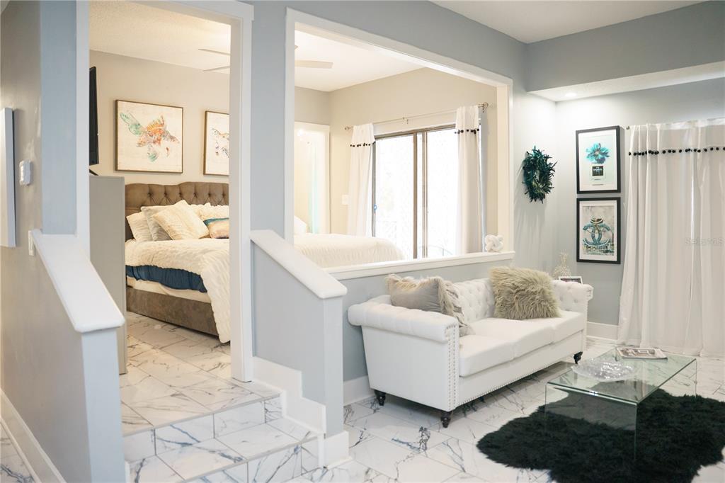A sunken bedroom with a tufted headboard is visible from a living area with white furniture — 4405 W FAIR OAKS AVENUE UNIT 2, TAMPA, FL