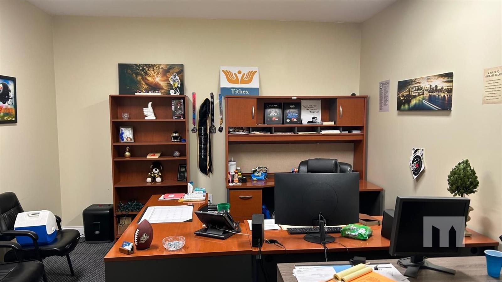 An office space features a wooden desk, a tall bookshelf, and various sports-themed wall decor — 9710 Stirling Road # 111A, Cooper City FL 33024, COOPER CITY, FL