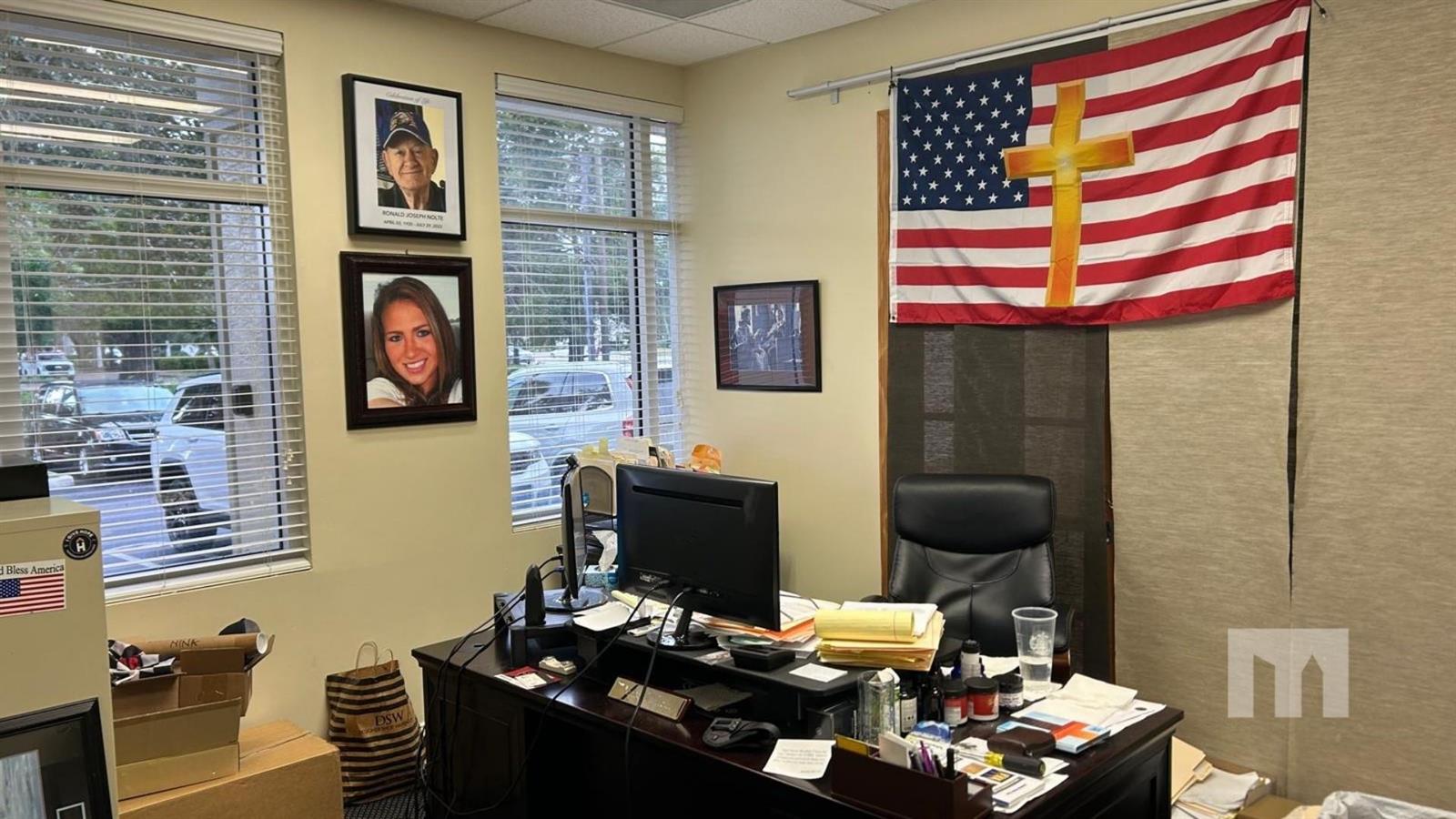 An office features a desk, computer, framed portraits, and an American flag with a cross — 9710 Stirling Road # 111A, Cooper City FL 33024, COOPER CITY, FL