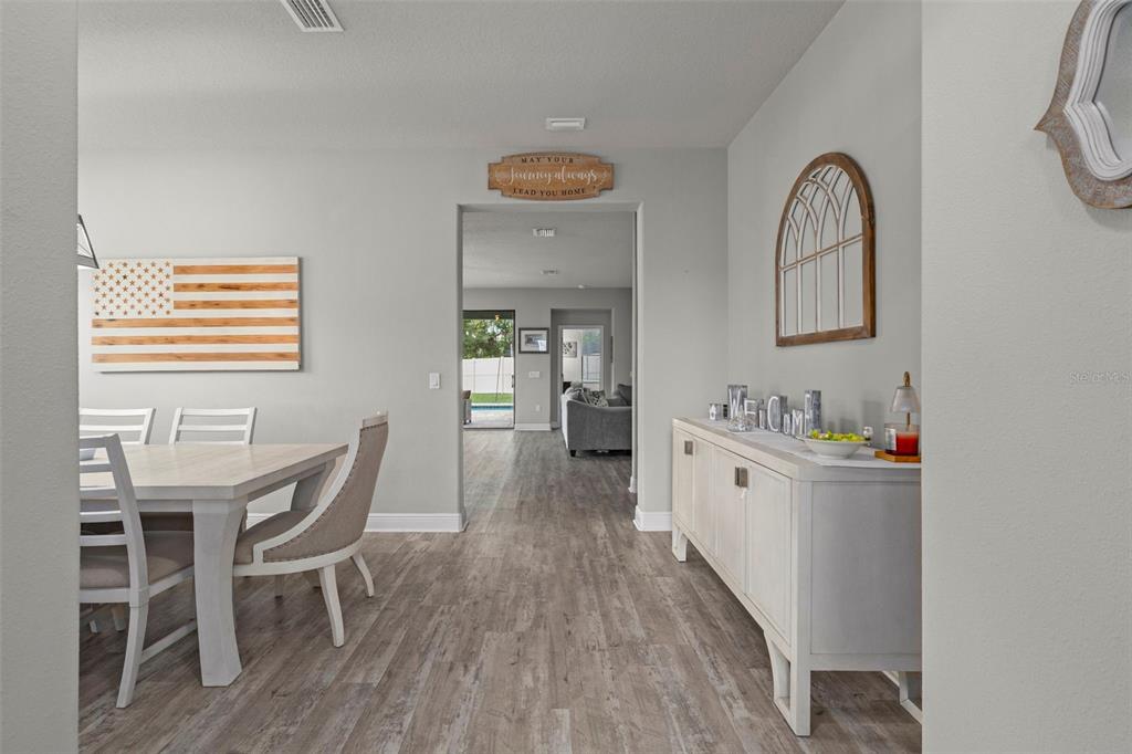 A dining area and hallway feature light wood-look flooring, gray walls, and a white sideboard — 1569 N RIVER CIRCLE, TARPON SPRINGS, FL