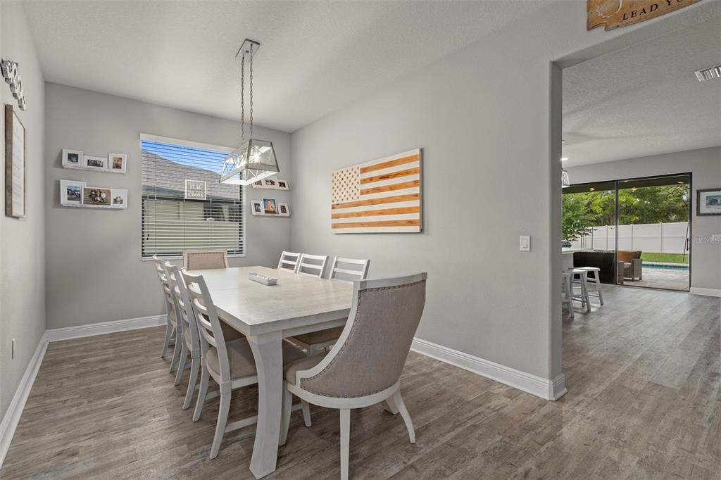 A dining room with a wooden table, upholstered chairs, and a wall-mounted American flag art — 1569 N RIVER CIRCLE, TARPON SPRINGS, FL