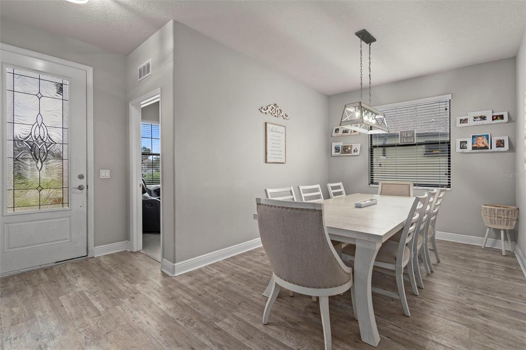 A dining room features a light wood table, upholstered chairs, and wood-look flooring — 1569 N RIVER CIRCLE, TARPON SPRINGS, FL