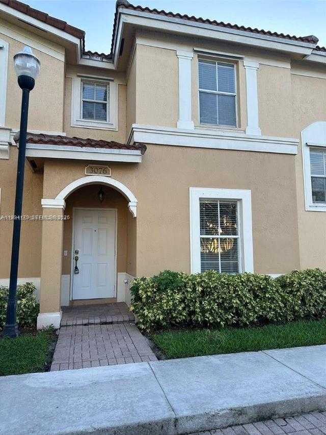 A two-story tan stucco townhouse features a white front door and a brick walkway — 3076 SW 129th Ave # 152, Miramar FL 33027, MIRAMAR, FL