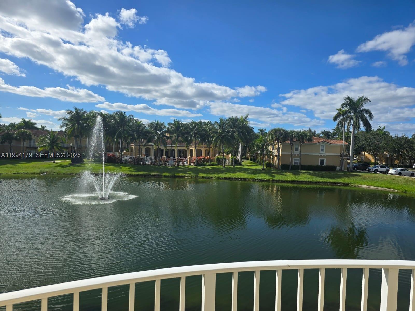 A view of a pond with a fountain, palm trees, and apartment buildings — 3076 SW 129th Ave # 152, Miramar FL 33027, MIRAMAR, FL
