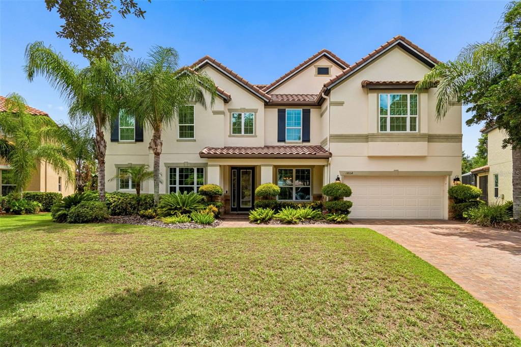 A two-story suburban house with a tiled roof, beige stucco exterior, and a paved driveway — 1804 BELLA CASA COURT, TAMPA, FL