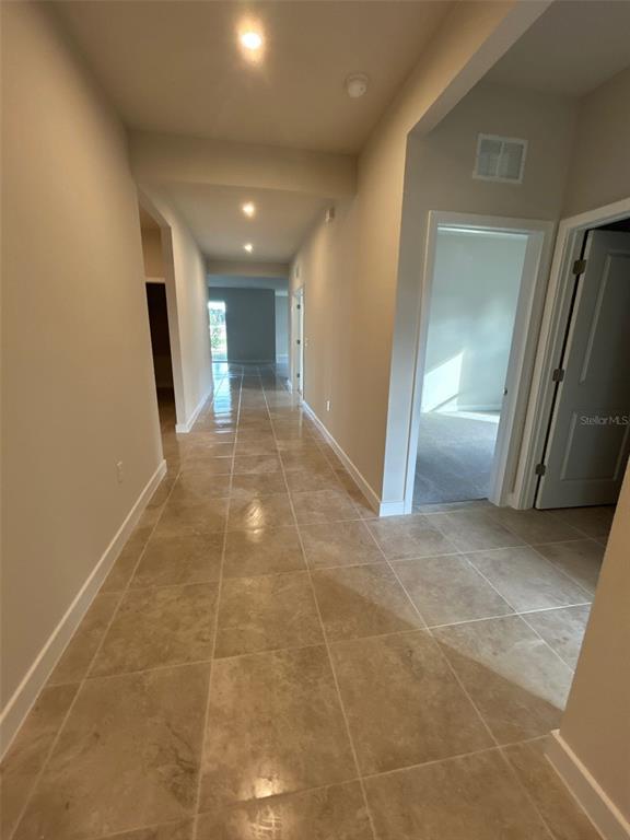 A long hallway with light-colored tile flooring leads toward an open living area — 10918 SW 72ND CIRCLE, OCALA, FL