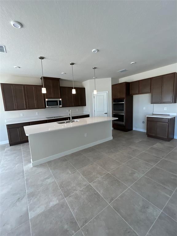 A kitchen features dark wood cabinets, a white island countertop, and light gray tile flooring — 10918 SW 72ND CIRCLE, OCALA, FL