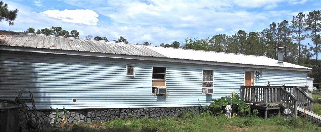 A light blue mobile home with a metal roof and a wooden deck — 10397 NW GAINESVILLE ROAD, OCALA, FL