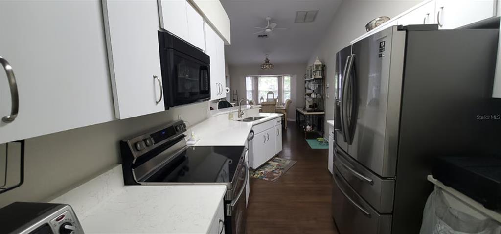 A kitchen features white cabinets, stainless steel appliances, and dark wood flooring — 2534 N BRENTWOOD CIRCLE, LECANTO, FL