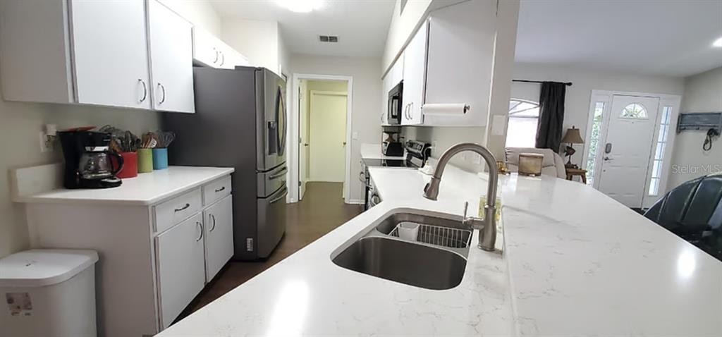 A kitchen features white cabinets, a stainless steel refrigerator, and a white quartz countertop — 2534 N BRENTWOOD CIRCLE, LECANTO, FL
