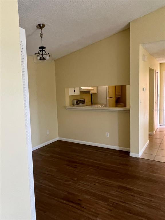 A dining area with wood-look flooring and a pass-through window into the kitchen — 5213 VIA HACIENDA CIRCLE UNIT 306, ORLANDO, FL