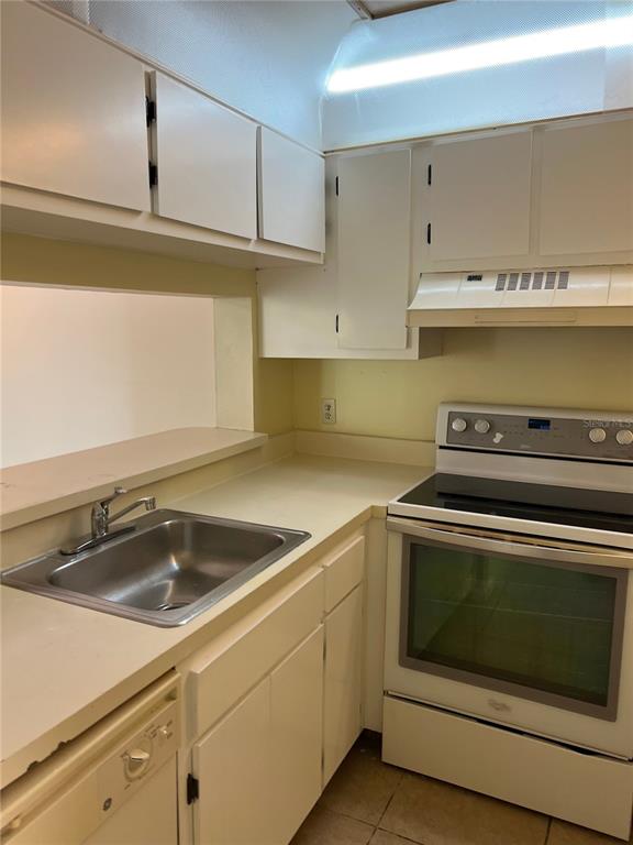 A kitchen features white cabinets, a stainless steel sink, and a white electric range — 5213 VIA HACIENDA CIRCLE UNIT 306, ORLANDO, FL