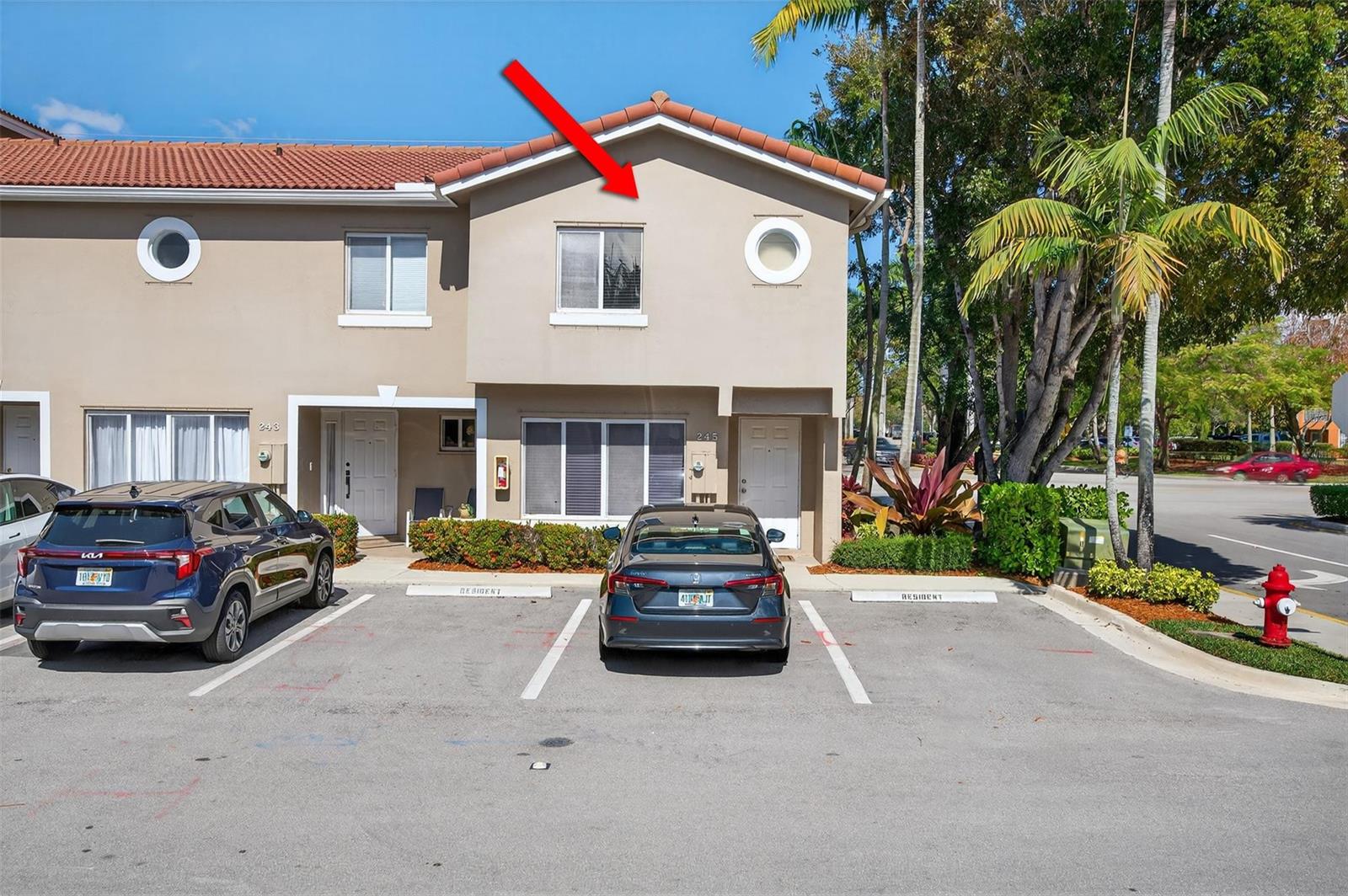 Exterior view of a two-story townhouse with a red arrow pointing to an upper window — 245 Riviera Circle # 245, Weston FL 33326, WESTON, FL