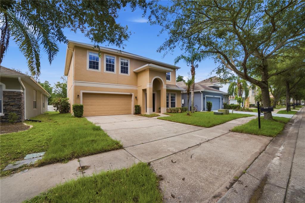 A two-story tan stucco house with a two-car garage and a paved driveway — 5341 PEPPER BRUSH COVE, APOPKA, FL