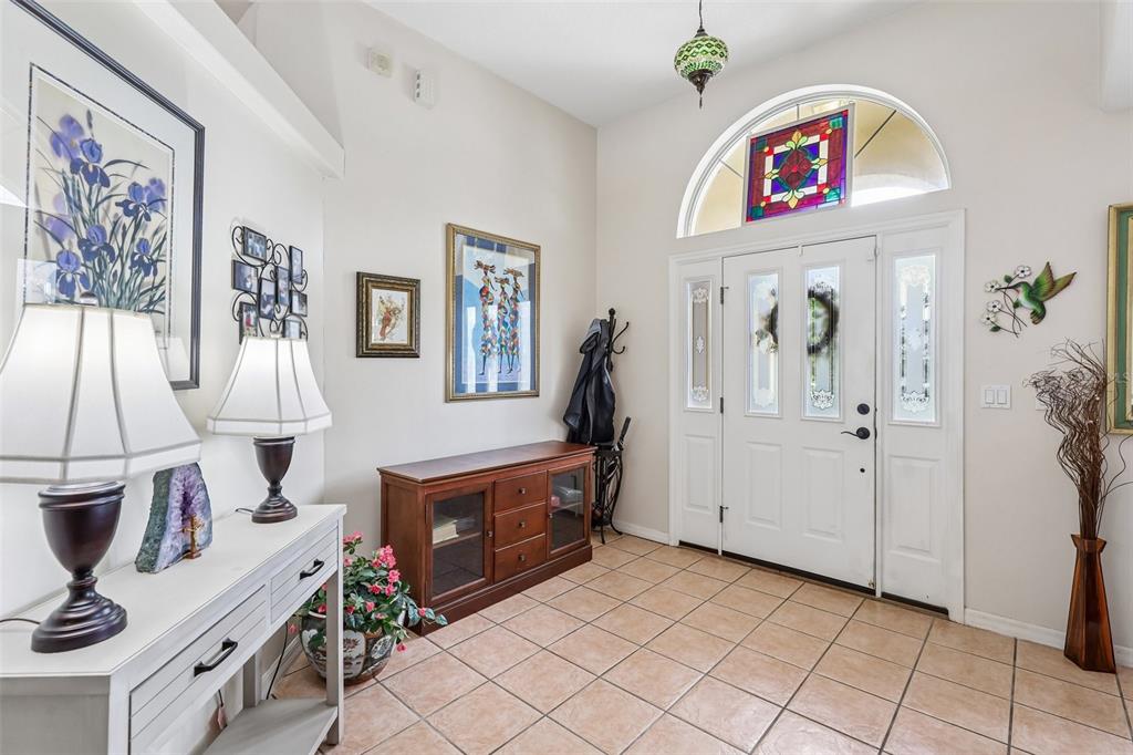An entryway features tile flooring, a wooden console table, a white door, and stained-glass accents — 60 WOODBURY DRIVE, PALM COAST, FL