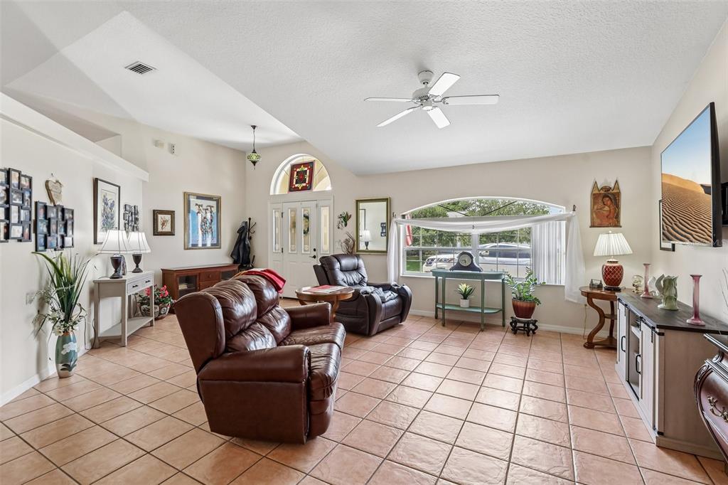 A living room features tile flooring, a vaulted ceiling with a fan, and leather furniture — 60 WOODBURY DRIVE, PALM COAST, FL