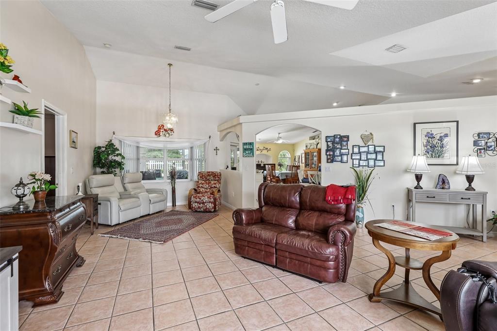 A living room features tile flooring, vaulted ceilings, a brown leather sofa, and neutral walls — 60 WOODBURY DRIVE, PALM COAST, FL
