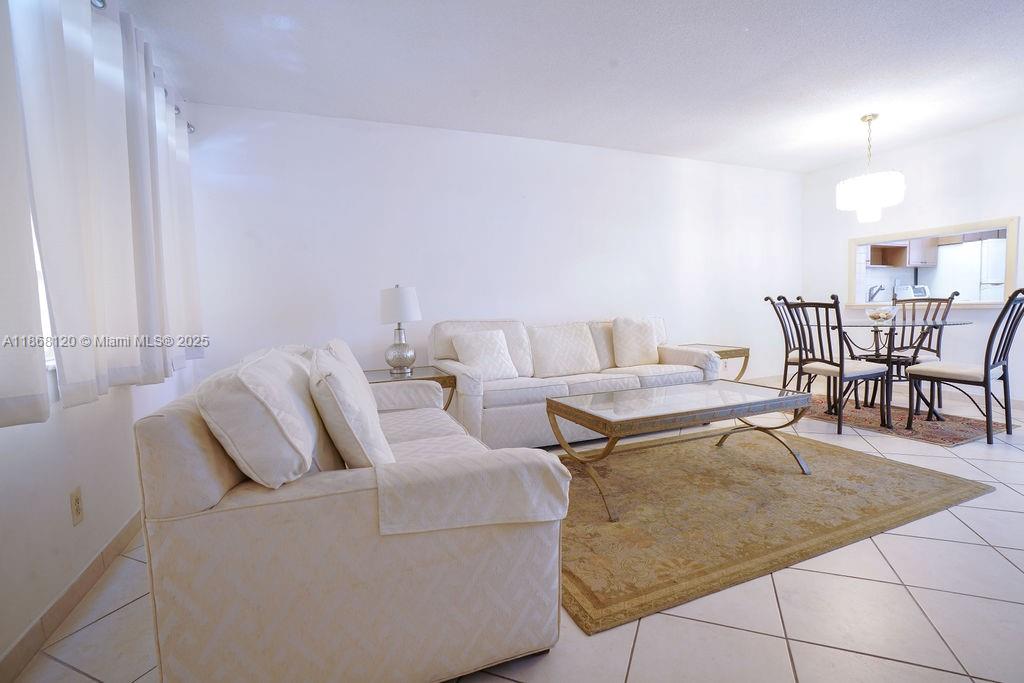 A living room features white sofas, a glass coffee table, and a dining area — 215 SE 3rd Ave # 401D, Hallandale Beach FL 33009, HALLANDALE BEACH, FL