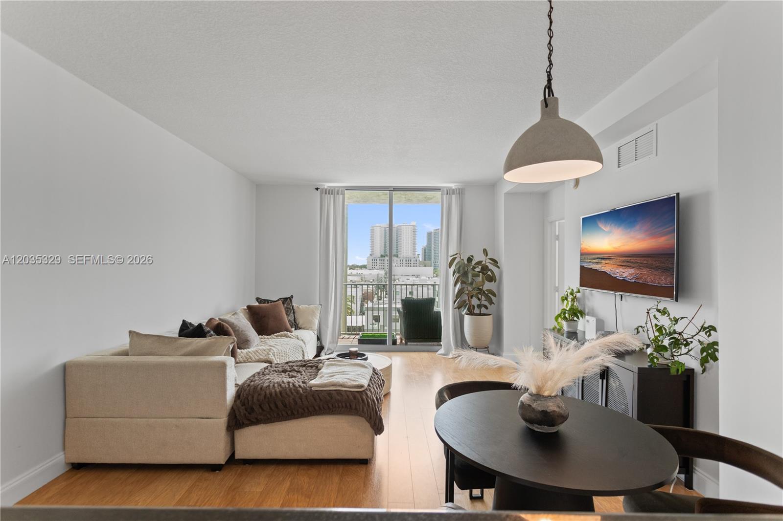 A living and dining area features light wood floors, a sectional sofa, and a balcony — 140 S Dixie Hwy # 417, Hollywood FL 33020, HOLLYWOOD, FL