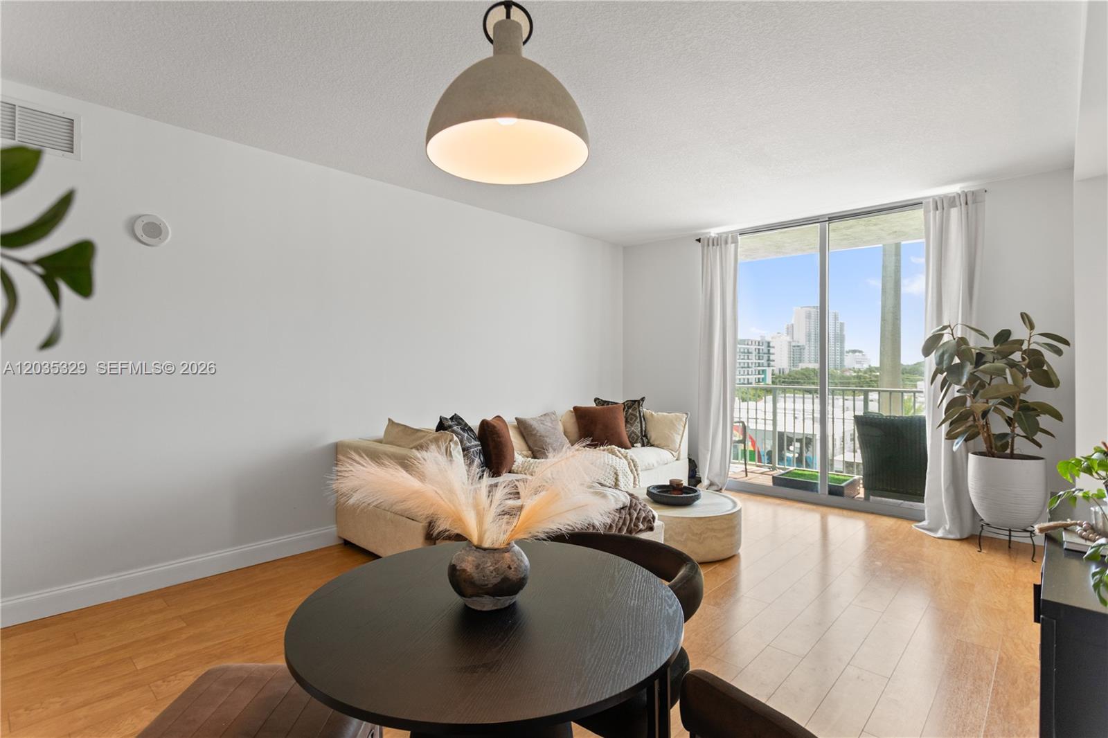 A living and dining area features light wood floors, a neutral sofa, and a balcony — 140 S Dixie Hwy # 417, Hollywood FL 33020, HOLLYWOOD, FL