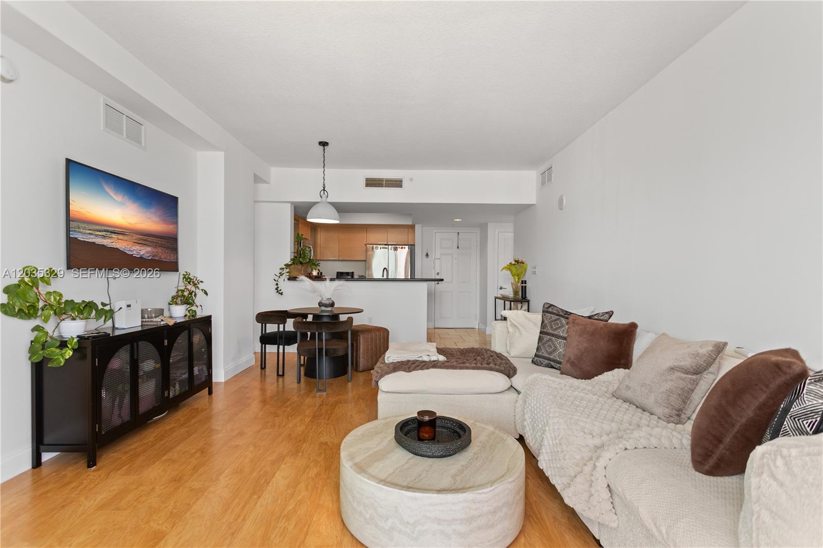 A living room with light wood floors, a sectional sofa, and an open kitchen area — 140 S Dixie Hwy # 417, Hollywood FL 33020, HOLLYWOOD, FL
