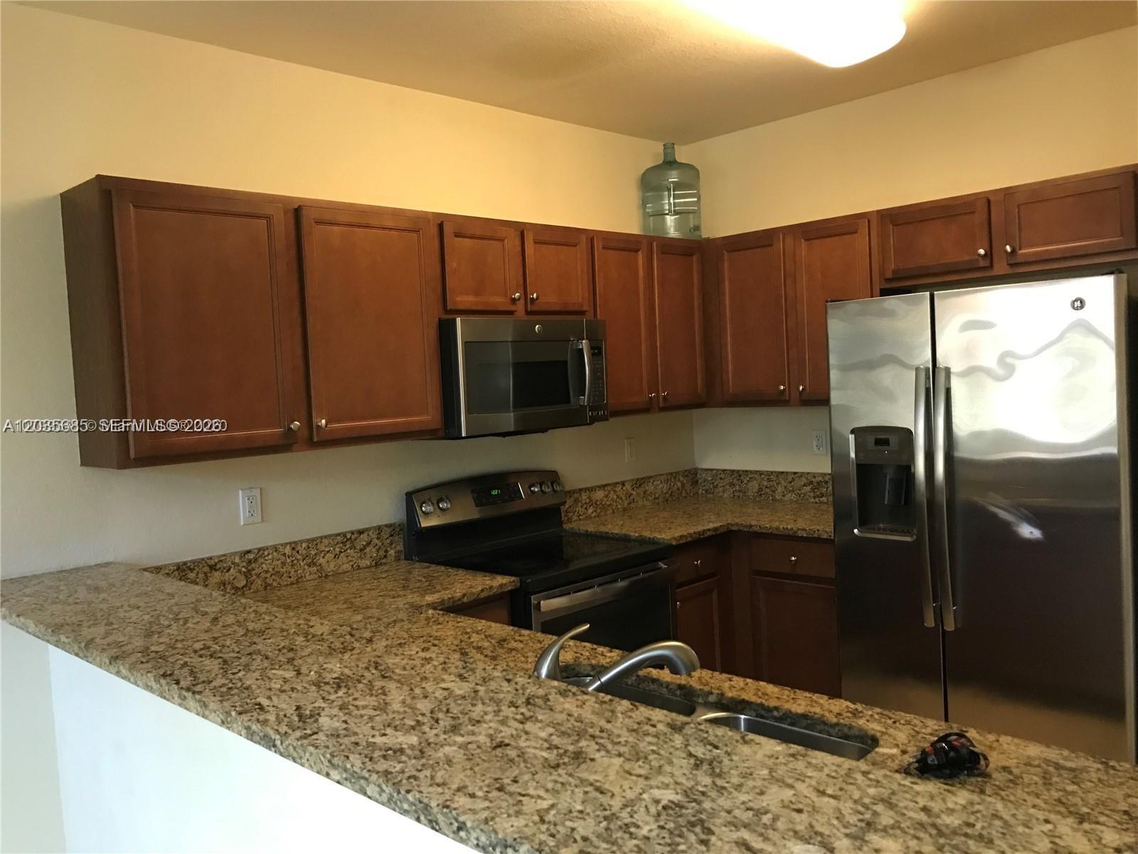 A kitchen features wood cabinets, granite countertops, and stainless steel appliances — 8900 NW 97th Ave # 212, Doral FL 33178, DORAL, FL