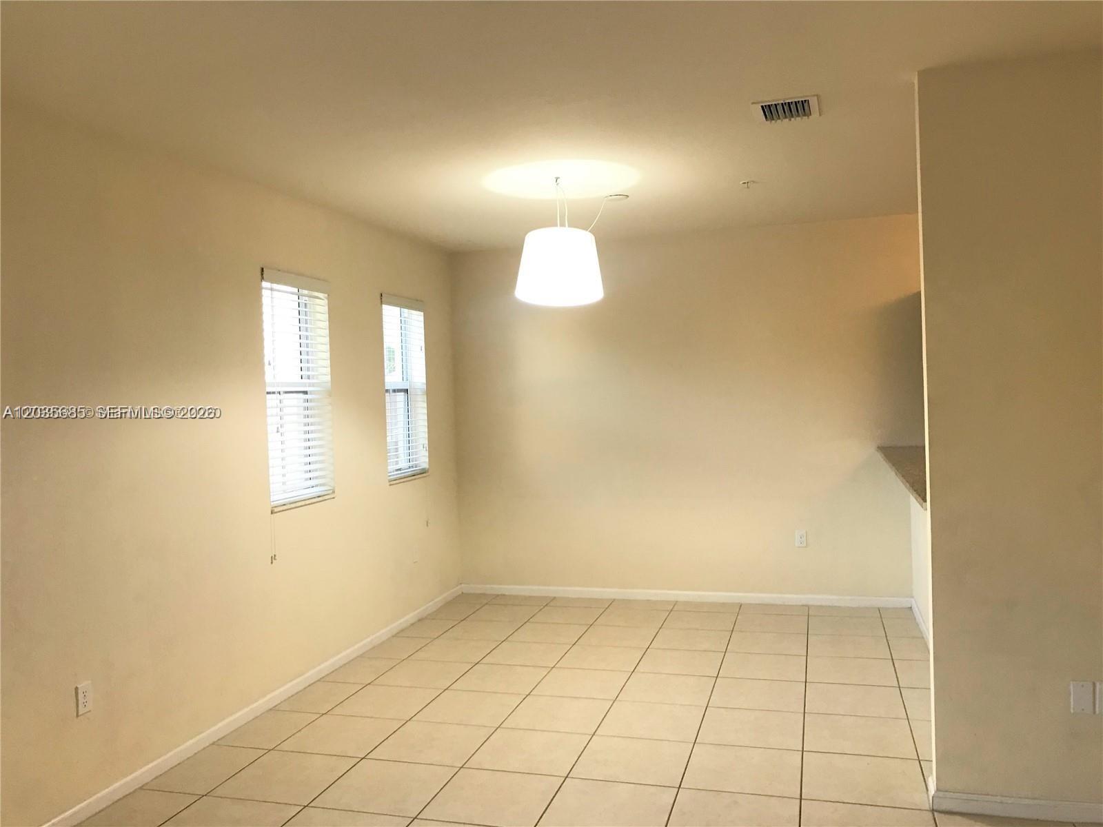 This dining area features light-colored floor tiles, two windows with blinds, and a pendant light — 8900 NW 97th Ave # 212, Doral FL 33178, DORAL, FL