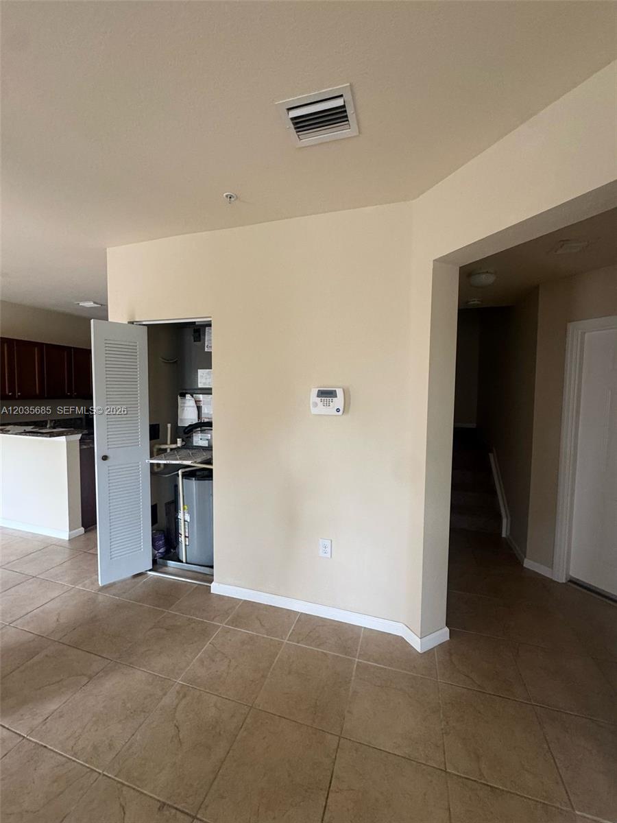 This interior view shows a tiled room with an open utility closet and a thermostat — 8900 NW 97th Ave # 212, Doral FL 33178, DORAL, FL