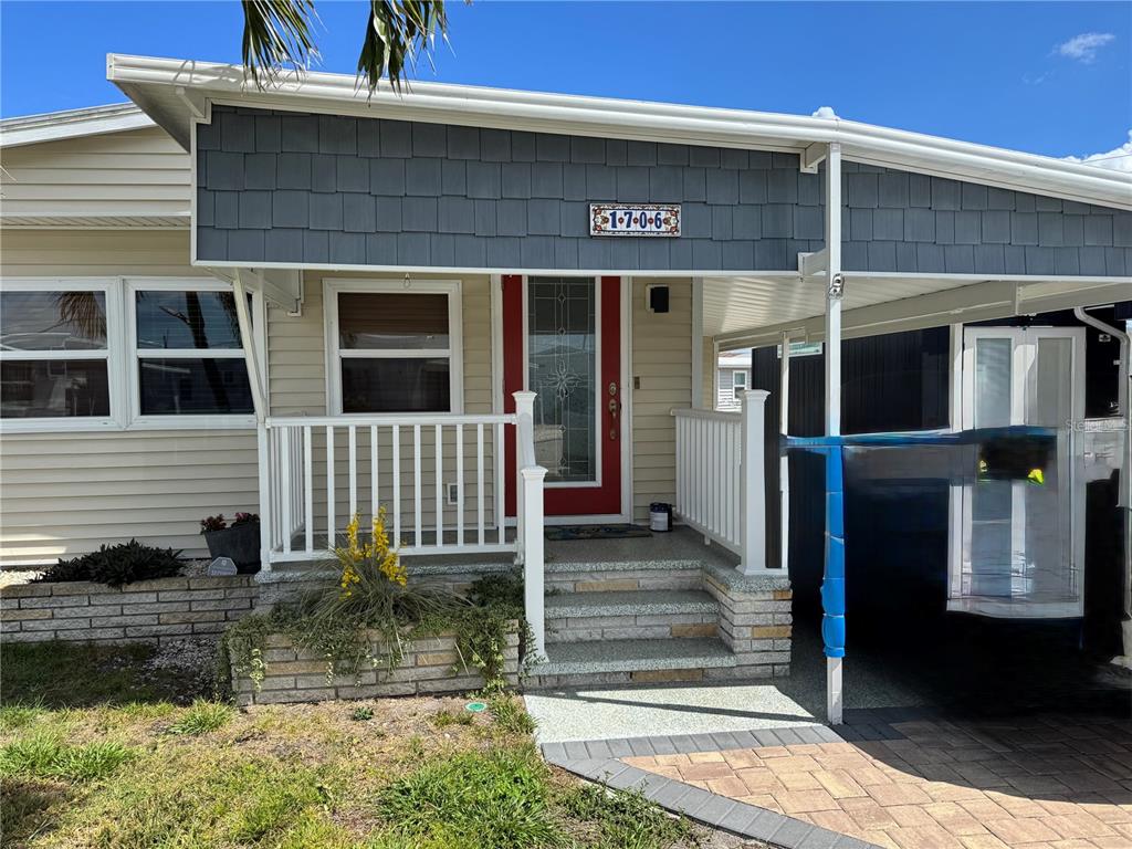 The exterior of a manufactured home features a covered porch, brick steps, and a carport — 1706 WISCONSIN AVENUE, BRADENTON, FL