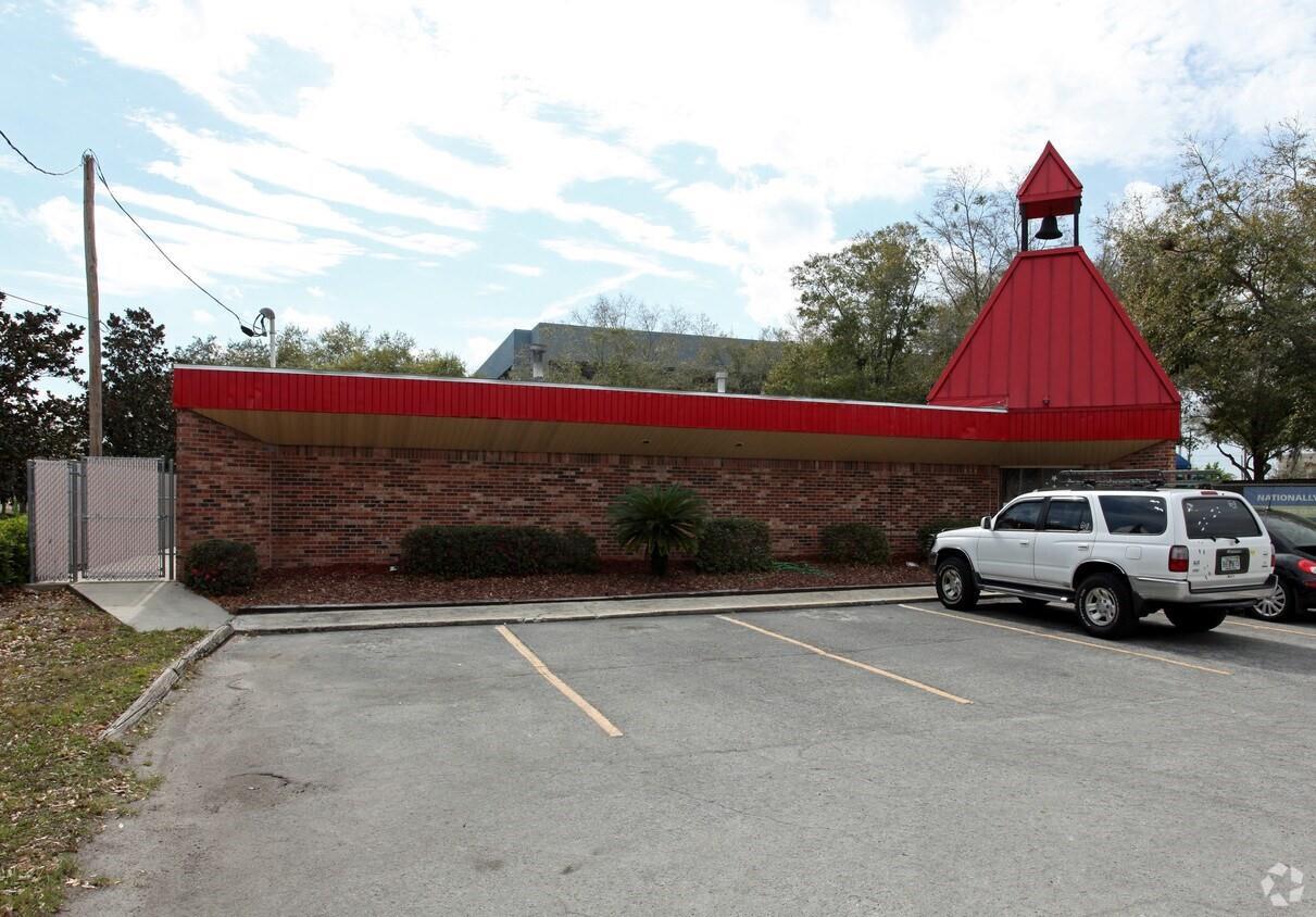 A brick building with a red roof and a bell tower stands beside a parking lot — 940 Winter Park Drive, FL 32707, FL